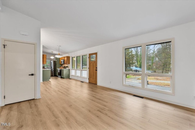 unfurnished living room featuring light wood-type flooring and visible vents