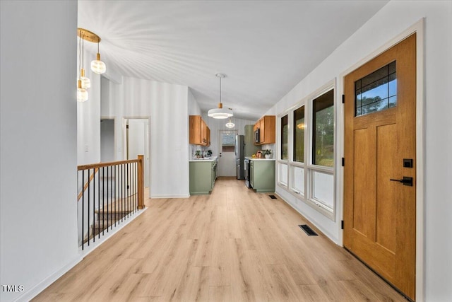 interior space featuring light wood-style floors, baseboards, visible vents, and vaulted ceiling