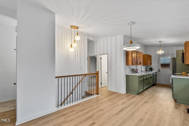 kitchen with light wood-style flooring, stainless steel appliances, light countertops, decorative backsplash, and green cabinetry