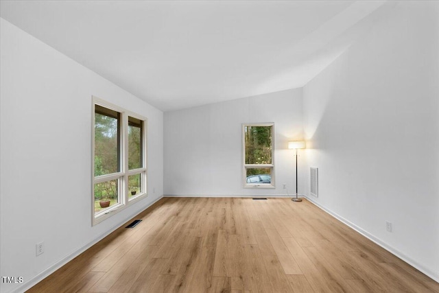 unfurnished room with light wood-type flooring, visible vents, and baseboards