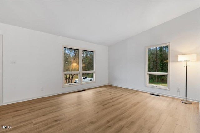 spare room featuring a healthy amount of sunlight, visible vents, and light wood finished floors