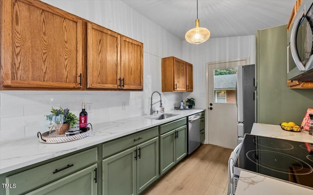 kitchen featuring a sink, green cabinets, appliances with stainless steel finishes, light wood finished floors, and tasteful backsplash