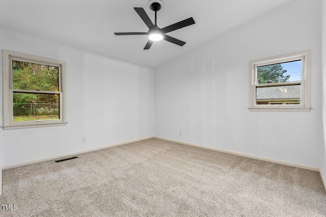 unfurnished room with lofted ceiling, carpet flooring, visible vents, and a healthy amount of sunlight