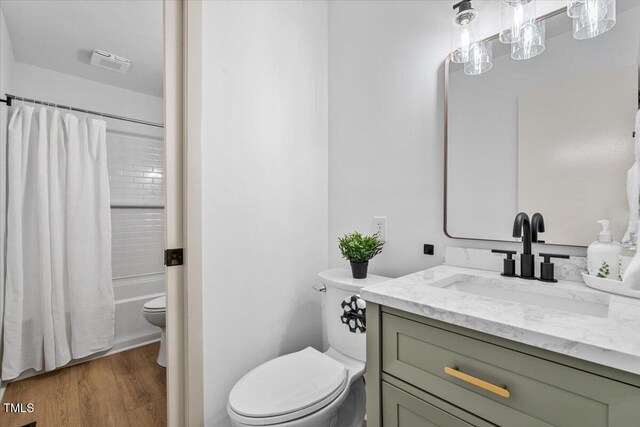 bathroom featuring toilet, shower / bath combo with shower curtain, wood finished floors, and vanity