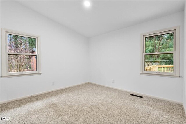 carpeted empty room with lofted ceiling, visible vents, plenty of natural light, and baseboards