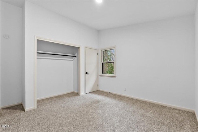 unfurnished bedroom with a closet, carpet flooring, vaulted ceiling, and baseboards