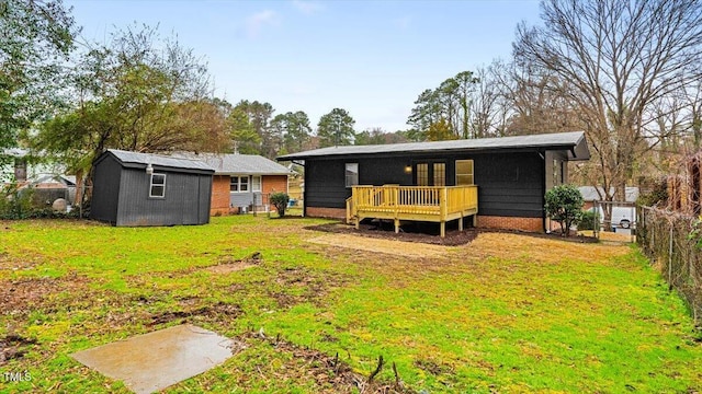 rear view of house featuring a wooden deck, a fenced backyard, a yard, a shed, and an outdoor structure