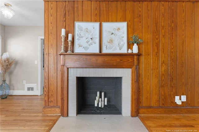 room details with a brick fireplace, visible vents, baseboards, and wood finished floors