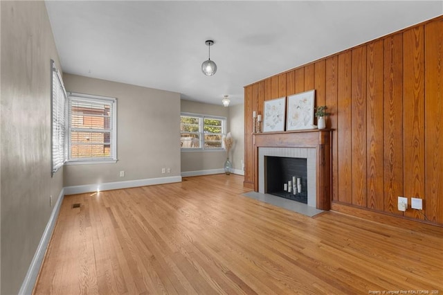 unfurnished living room featuring light wood-style flooring, a fireplace, visible vents, and baseboards