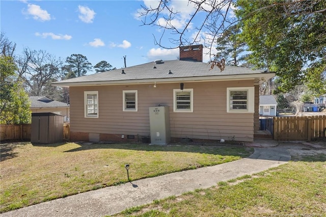 back of property featuring an outbuilding, fence, a yard, crawl space, and a chimney