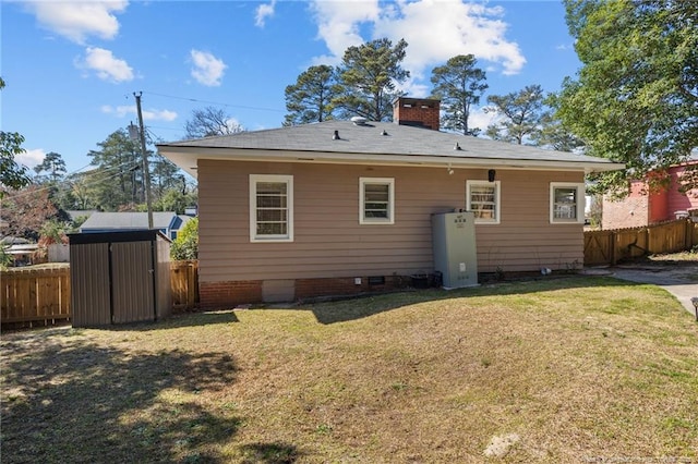 back of property featuring a storage unit, fence, a lawn, and an outbuilding