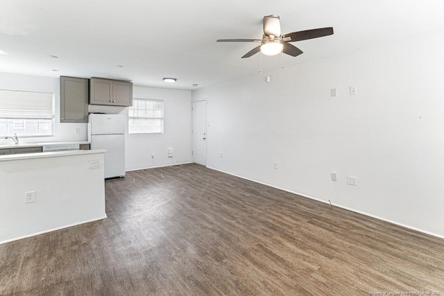 unfurnished living room featuring ceiling fan and dark wood-style flooring