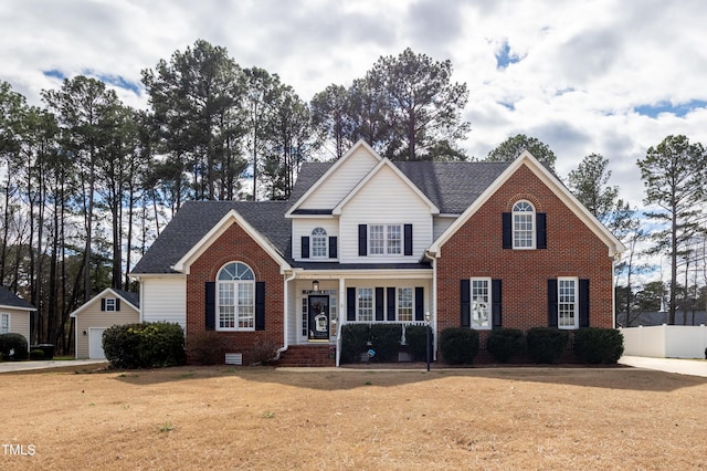 view of front of property with brick siding, a front lawn, fence, a garage, and an outdoor structure