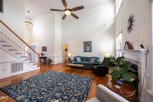 living area with stairs, a high ceiling, wood finished floors, and visible vents