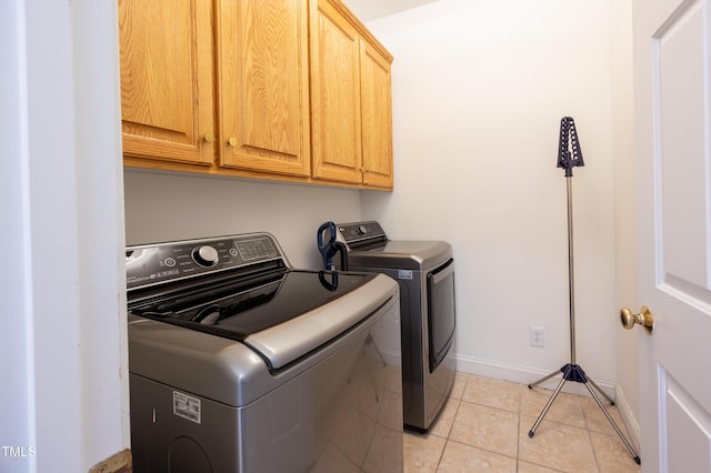 laundry area with light tile patterned floors, baseboards, cabinet space, and washing machine and clothes dryer