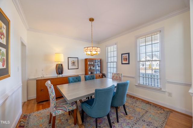 dining area with crown molding, baseboards, and light wood finished floors