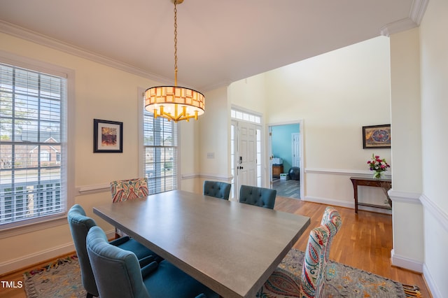 dining space with crown molding, light wood-style flooring, plenty of natural light, and baseboards