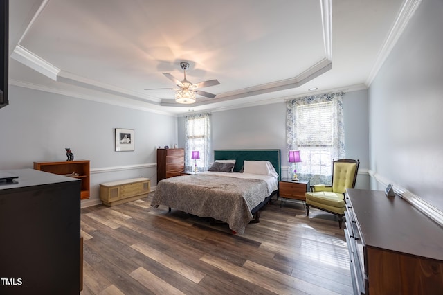 bedroom featuring a tray ceiling, ornamental molding, dark wood-style flooring, and ceiling fan