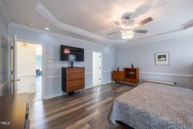 bedroom with a tray ceiling, wood finished floors, and ornamental molding