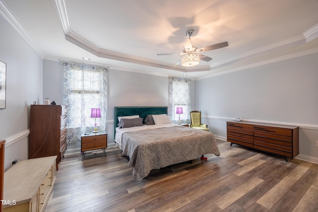 bedroom featuring a tray ceiling, wood-type flooring, and ornamental molding