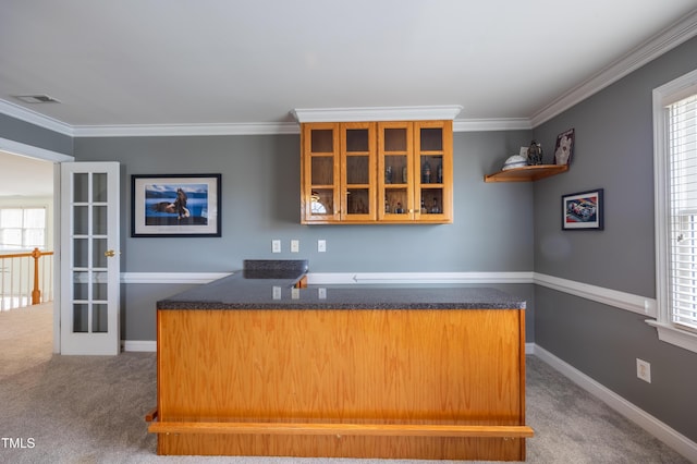 kitchen featuring glass insert cabinets, crown molding, baseboards, and carpet floors