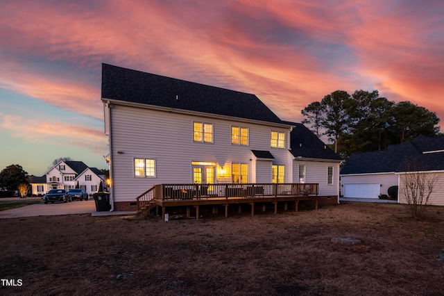 back of property at dusk featuring roof with shingles, a deck, a garage, crawl space, and an outdoor structure