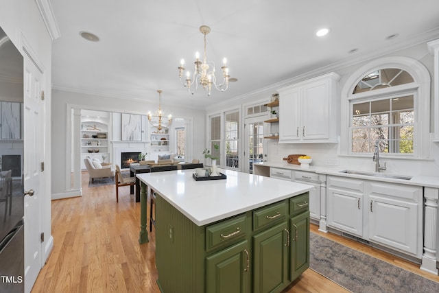 kitchen with a sink, white cabinetry, crown molding, green cabinetry, and a chandelier