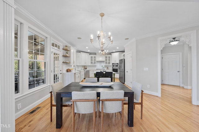 dining area featuring baseboards, visible vents, an inviting chandelier, ornamental molding, and light wood-type flooring