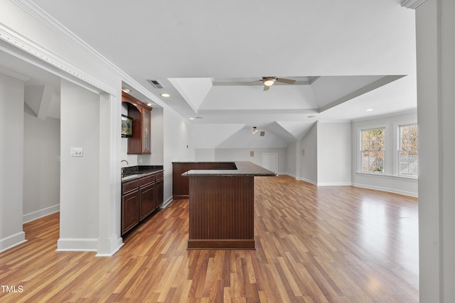 kitchen with dark countertops, a center island, baseboards, light wood-style floors, and a ceiling fan