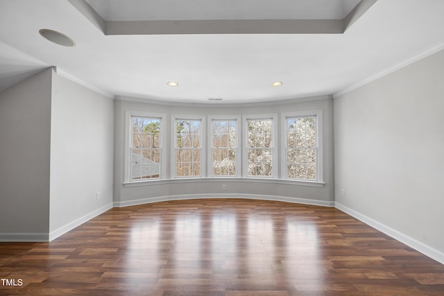 spare room featuring a healthy amount of sunlight, ornamental molding, baseboards, and wood finished floors