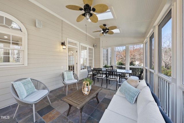 sunroom with lofted ceiling with skylight and a ceiling fan