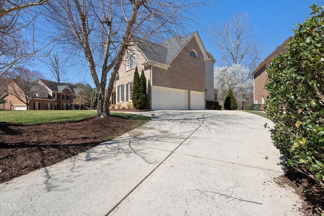 view of side of home featuring a garage, brick siding, and driveway