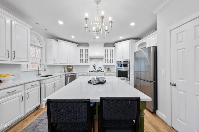 kitchen featuring a chandelier, white cabinetry, stainless steel appliances, and a sink