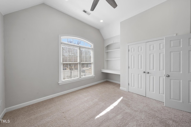 unfurnished bedroom featuring visible vents, lofted ceiling, a closet, carpet flooring, and baseboards