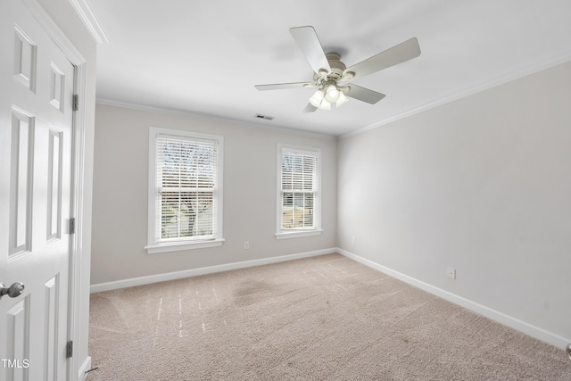 carpeted empty room featuring visible vents, baseboards, a ceiling fan, and crown molding