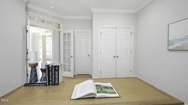 bedroom with crown molding, wood finished floors, a closet, and baseboards