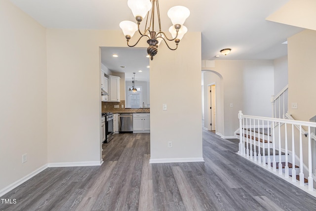 kitchen with white cabinets, a chandelier, stainless steel appliances, and arched walkways