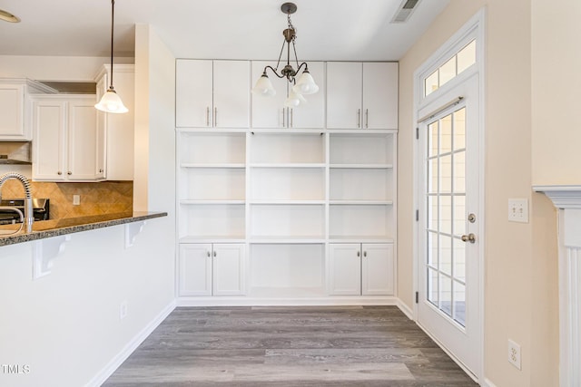 interior space featuring dark wood-type flooring, white cabinets, visible vents, and an inviting chandelier