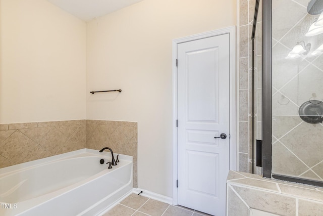 bathroom with tile patterned flooring, a tile shower, baseboards, and a bath