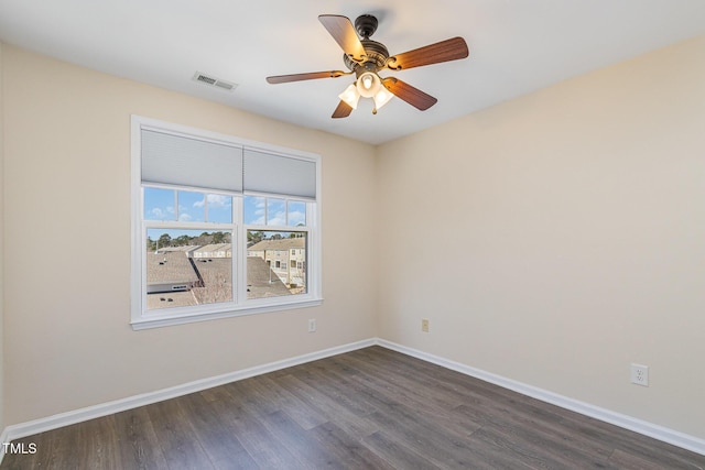 empty room with a ceiling fan, dark wood finished floors, visible vents, and baseboards