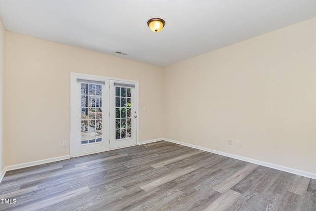 unfurnished room featuring visible vents, baseboards, and wood finished floors