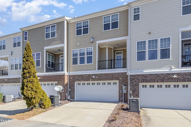 view of front of property featuring driveway, central AC, and brick siding