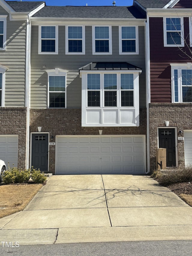 multi unit property with driveway, a garage, and brick siding