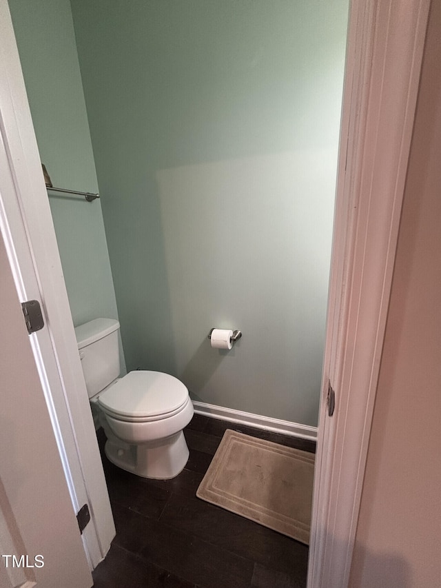 bathroom with baseboards, toilet, and wood finished floors