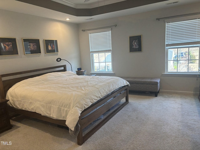 carpeted bedroom featuring ornamental molding, a raised ceiling, visible vents, and baseboards