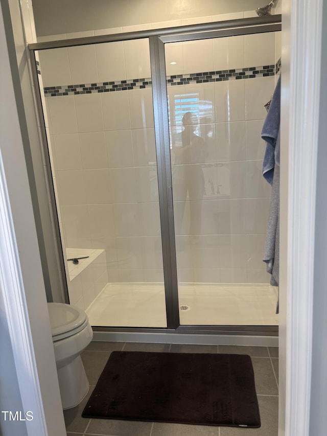 full bathroom with toilet, a shower stall, and tile patterned floors