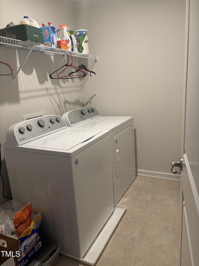 washroom featuring laundry area, light tile patterned floors, baseboards, and separate washer and dryer