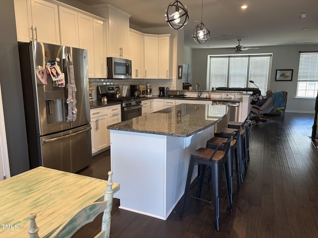 kitchen featuring stainless steel appliances, a center island, white cabinetry, and a sink