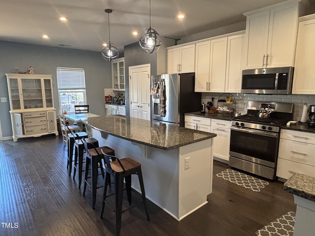 kitchen with stainless steel appliances, white cabinets, a kitchen island, and decorative backsplash