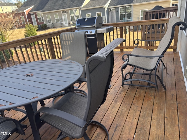 wooden terrace featuring outdoor dining space, a grill, and a residential view